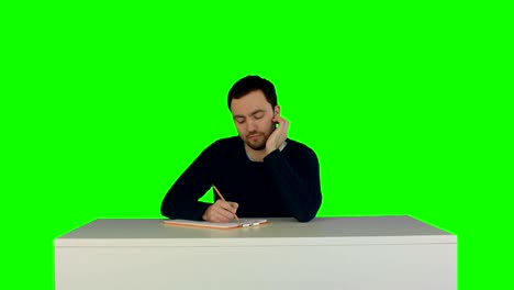pensive student listening to lecture in university and taking notes on a green screen