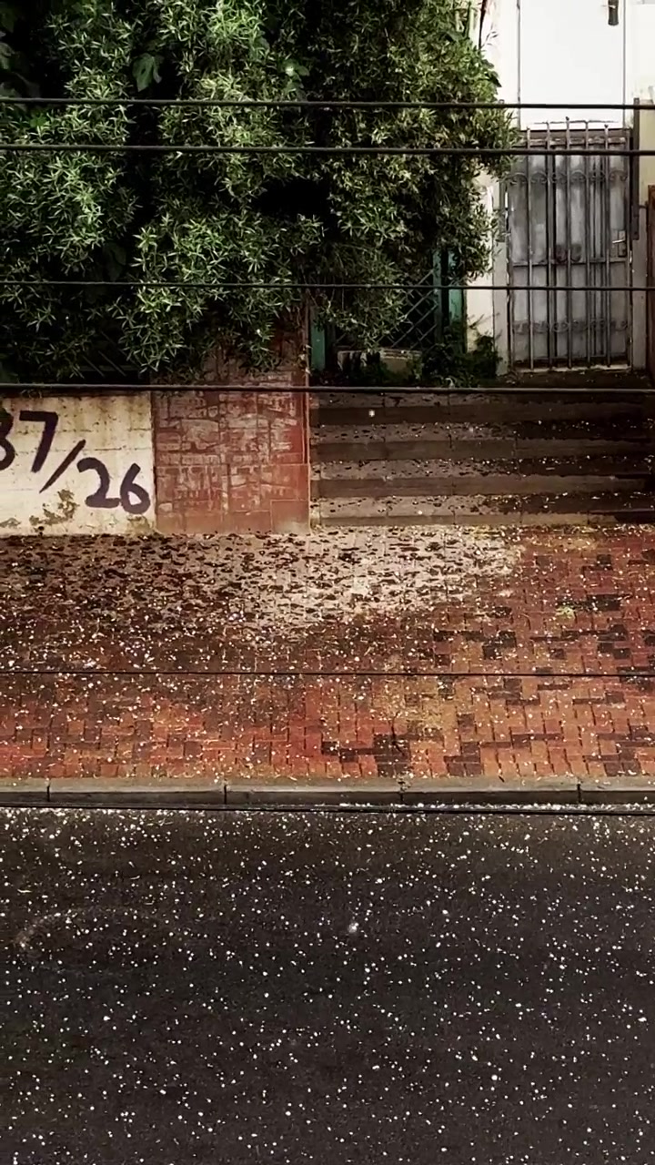 Hail falling on red brick sidewalk and city street