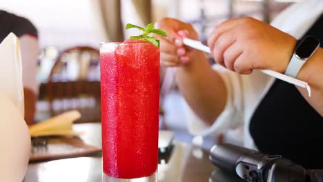 a person prepares a vibrant watermelon juice in a bright cafe setting, highlighting refreshing summer vibes and casual dining
