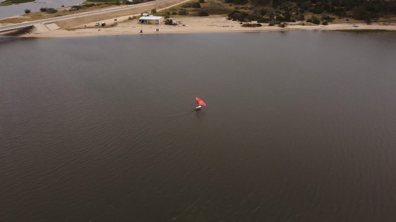 vista de pájaro de wind surfer, navegando solo en las aguas de laguna garzon