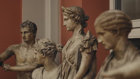 Close-up-of-multiple-ancient-antique-statues-standing-in-a-museum-with-moody-warm-lights