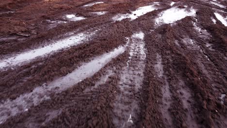 Frozen-tire-tracks-in-local-peat-deposit-in-winter-season,-dolly-backward