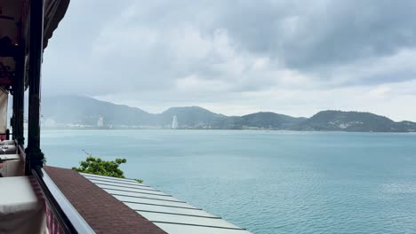 una vista serena de la playa de kalim desde un restaurante en phuket, tailandia, capturada durante un día lluvioso con cielos nublados