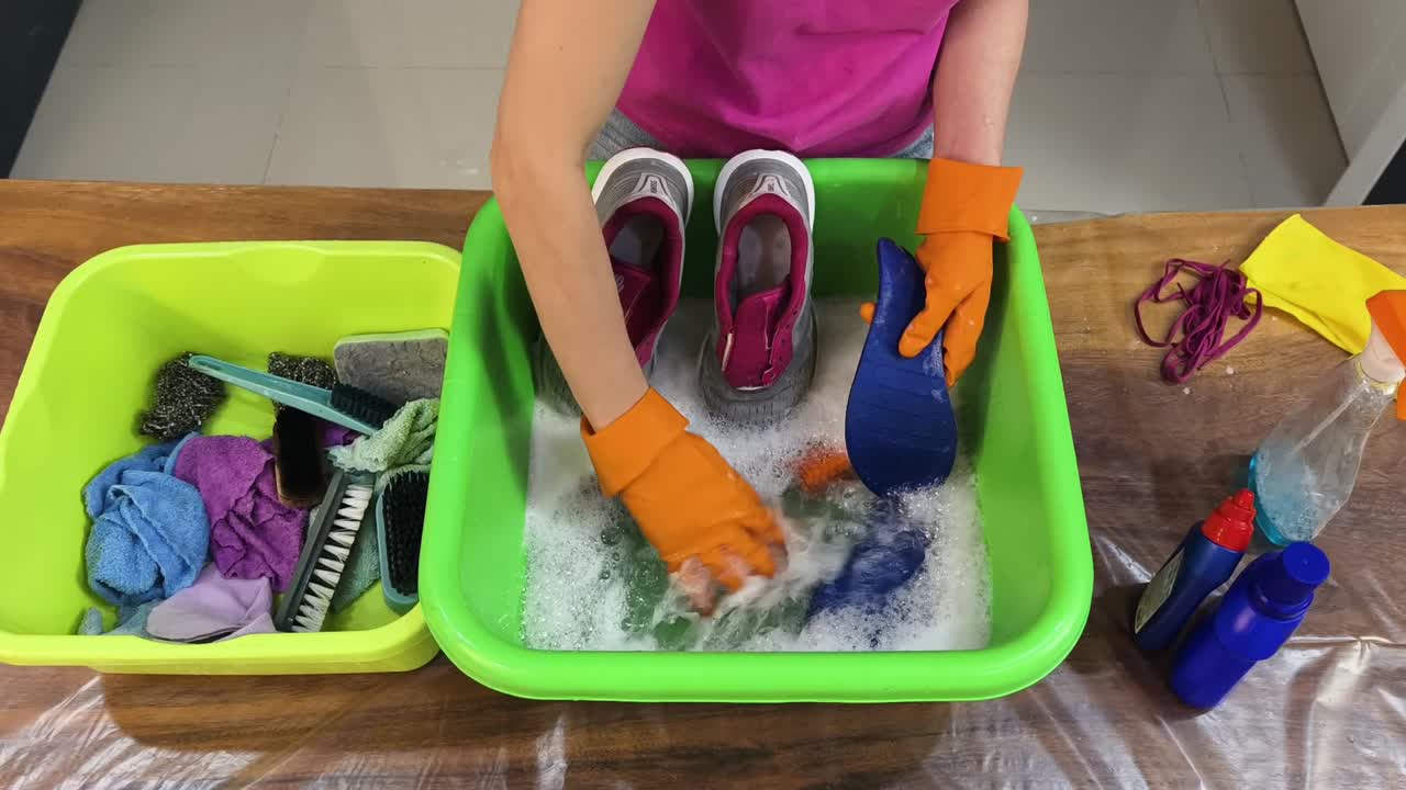 Washing shoes with orange gloves