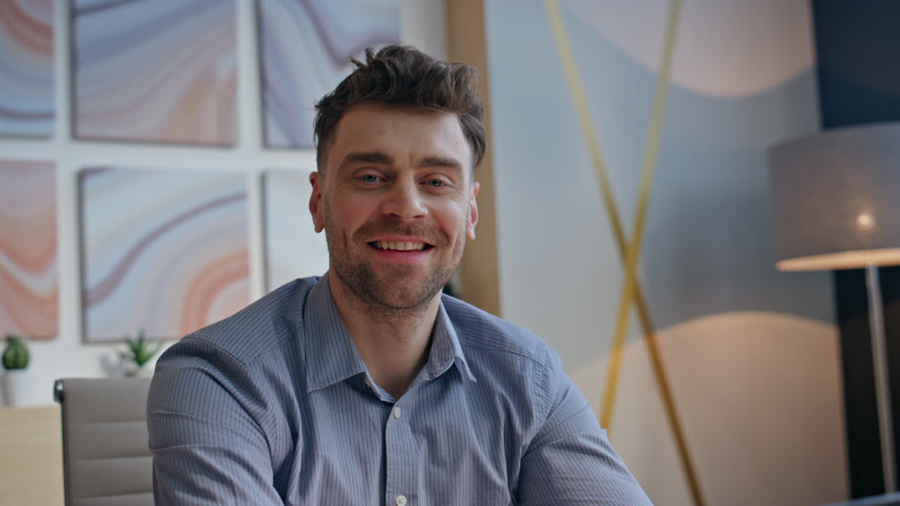 Smiling boss resting workplace at modern interior closeup. Man looking camera