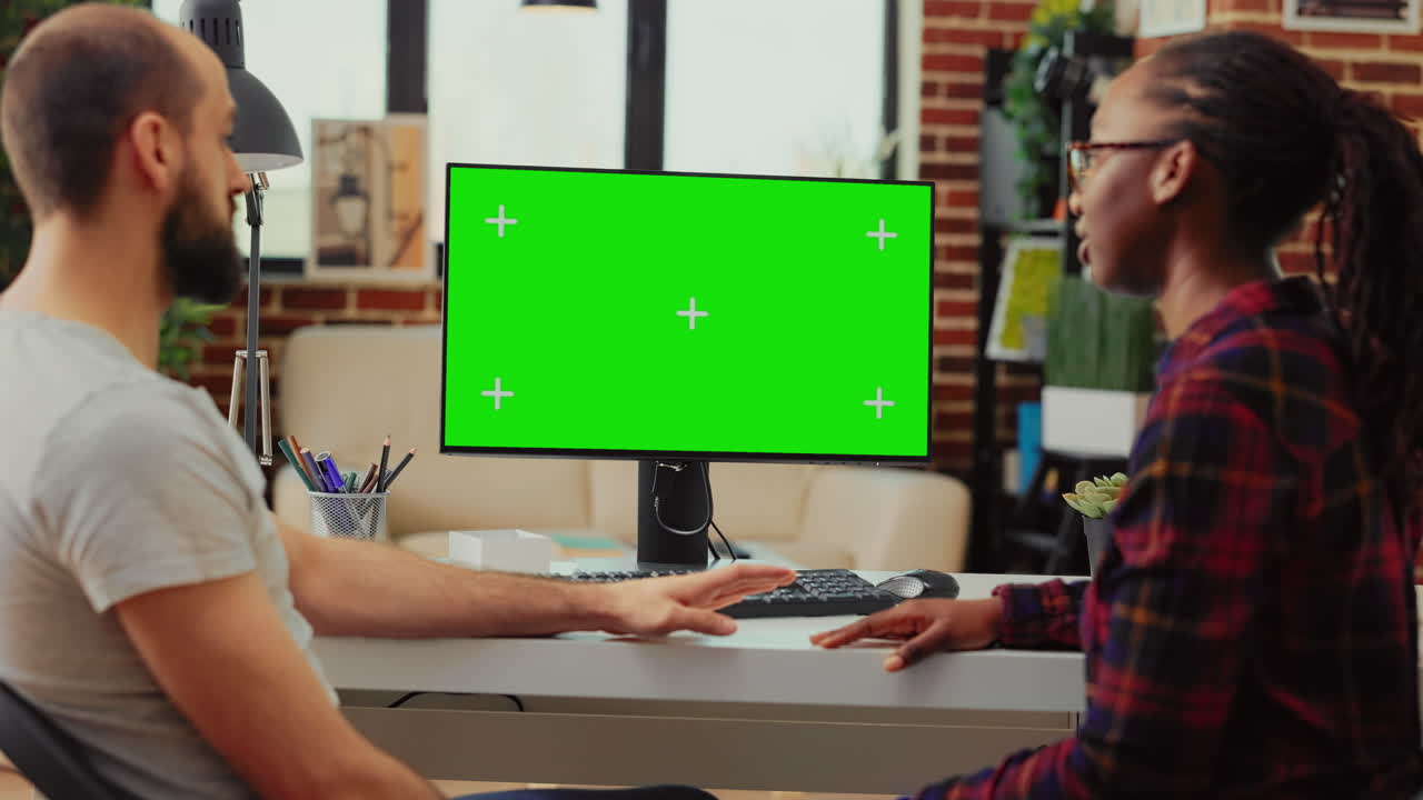 Diverse team working on computer with greenscreen at desk