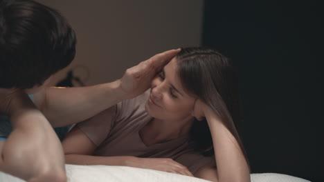 young couple lying in bed, woman and man sharing moments, face caress