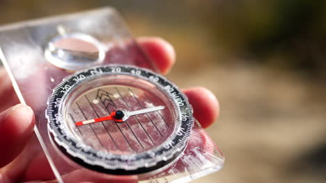 close up on the needle spinning of a magnetic compass finding north on a hike to stay on the trail and not get lost in the wilderness