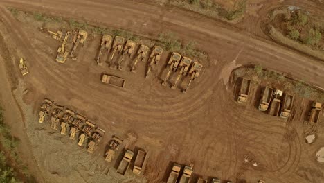 a fleet of dusty trucks and diggers lined up in the dirt at a nickel mine in taganito, philippines