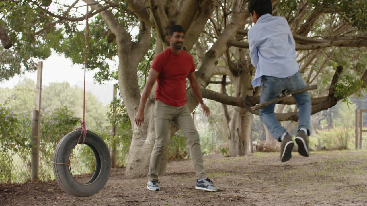 Pushing son on tire swing, Indian father and child enjoying outdoor playtime together