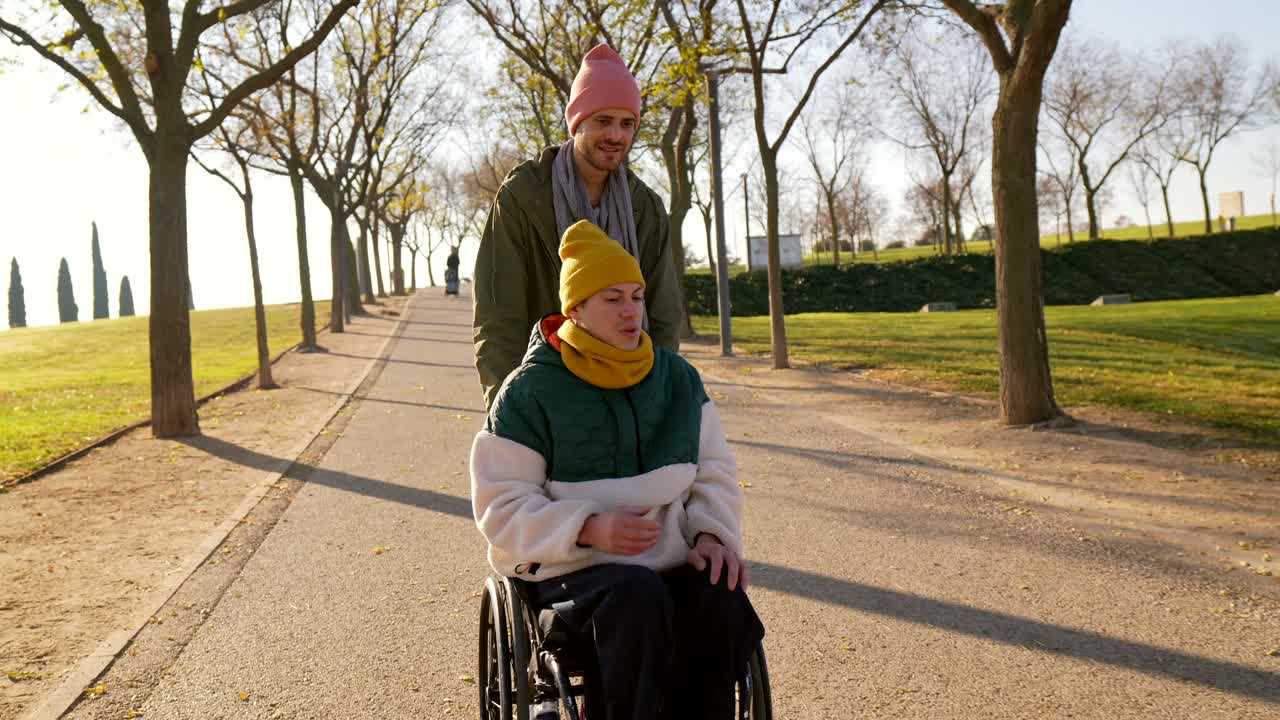 hombre empujando a una mujer en silla de ruedas en el parque