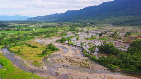 panorama of a paddy fields after harvest flooded with water near quarry stone crushing area in southern leyte, philippines