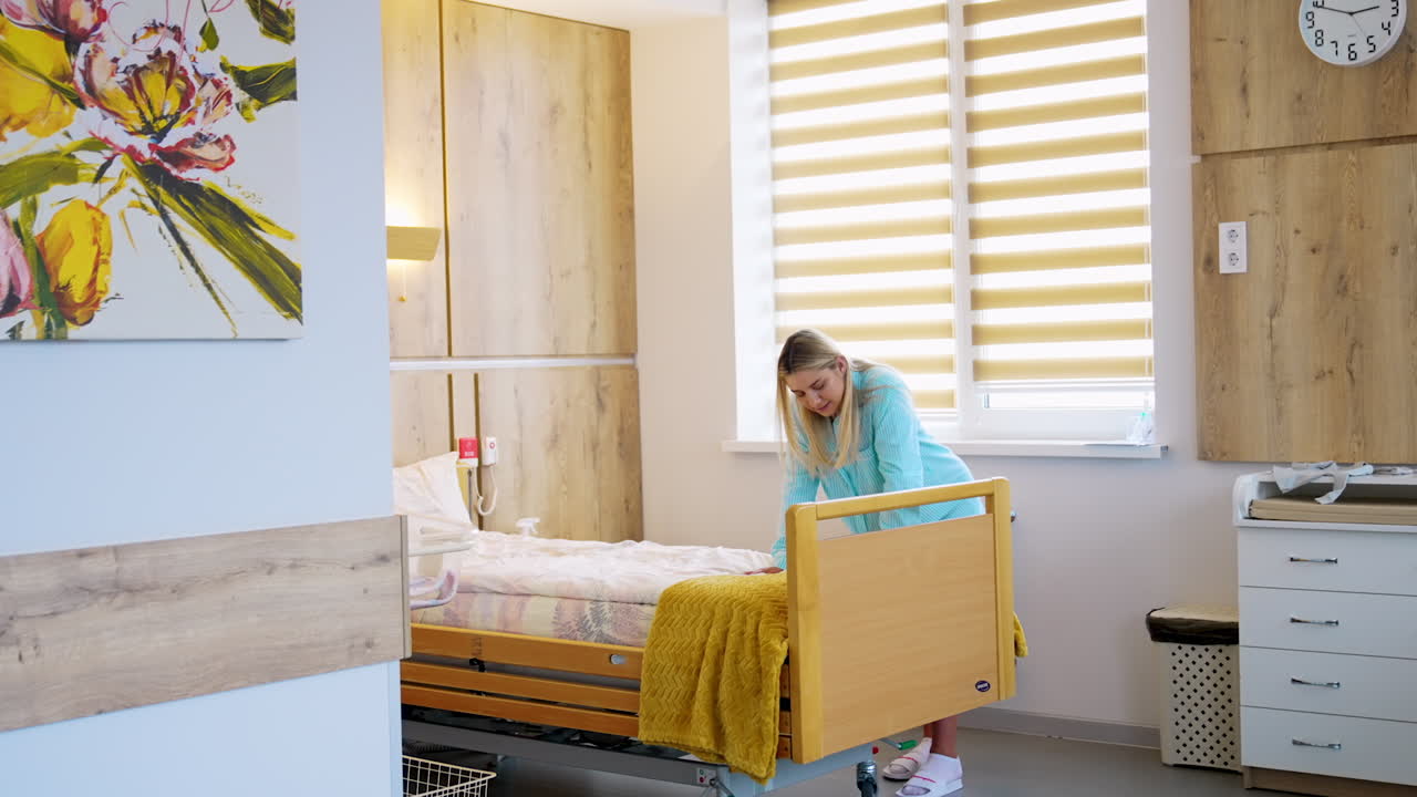 Pregnant blonde lady in the hospital ward. Lady leans on the bed to relief pain from contractions.