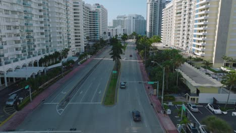 forwards tracking of vehicles driving on multilane trunk road in modern urban borough. palm trees along road. miami, usa