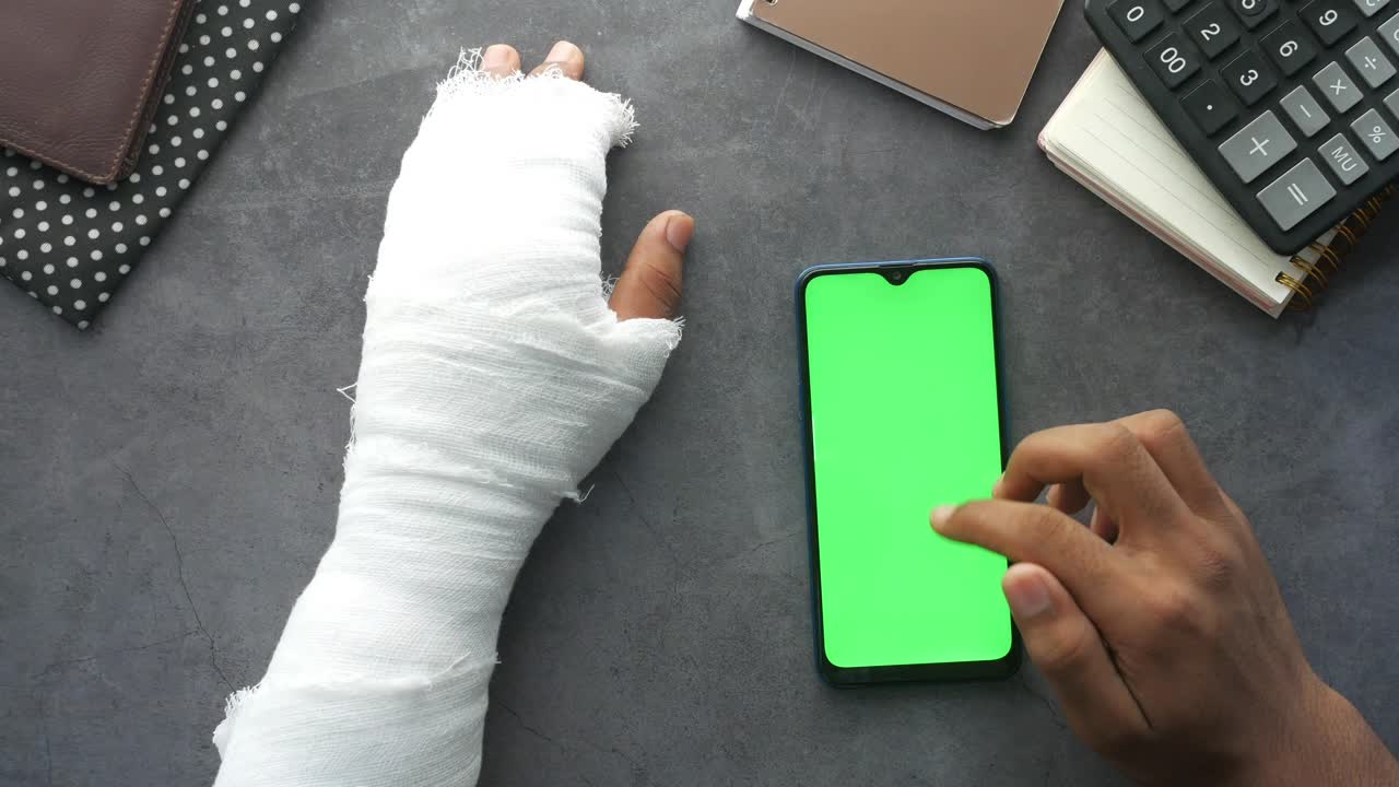 Braccio infortunato con telefono a schermo verde