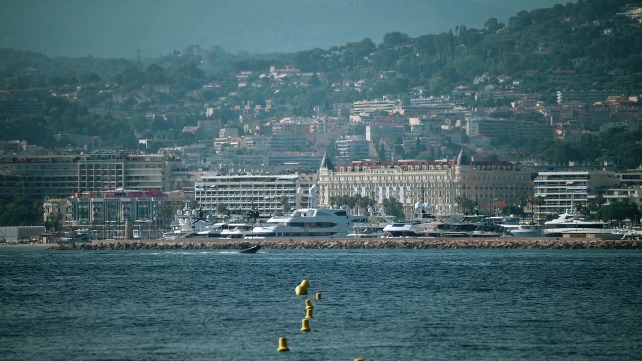 Panorama urbano di Cannes sulla Costa Azzurra con l'iconico hotel InterContinental Carlton, yacht di lusso nel porto e il Mar Mediterraneo blu, Cannes, Francia