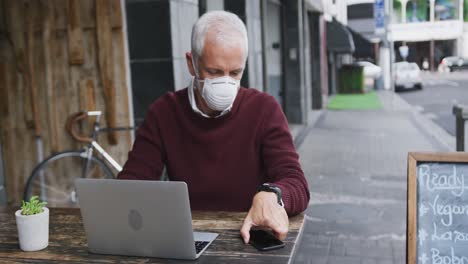 hombre caucásico fuera y alrededor en un café con una máscara facial contra el coronavirus