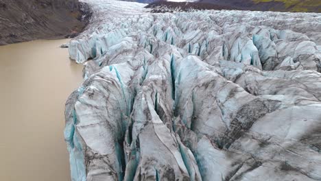 volando sobre los glaciares de sólheimajökull, las grietas azul turquesa están cubiertas de polvo negro