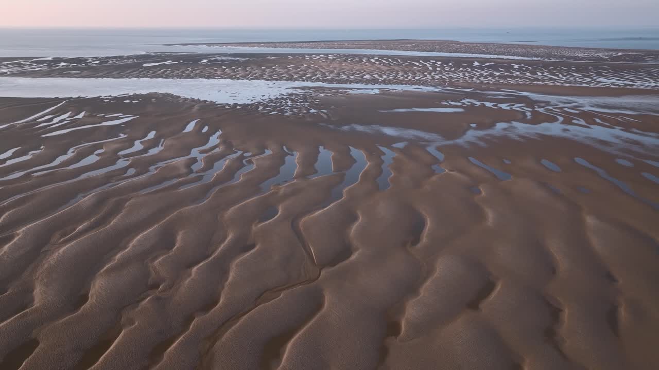 Sand patterns and seawater pools on tidal sand flats with view to the horizon, near sunset. Fleetwood, Lancashire, UK.