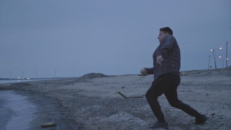 caucasian man skipping rocks at a cold lake