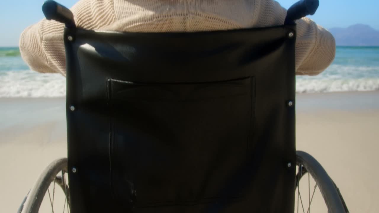 Rear view of disabled senior woman with arms outstretched on the beach 4k