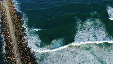 looking down over gold coast seawall with waves crashing in at sunset