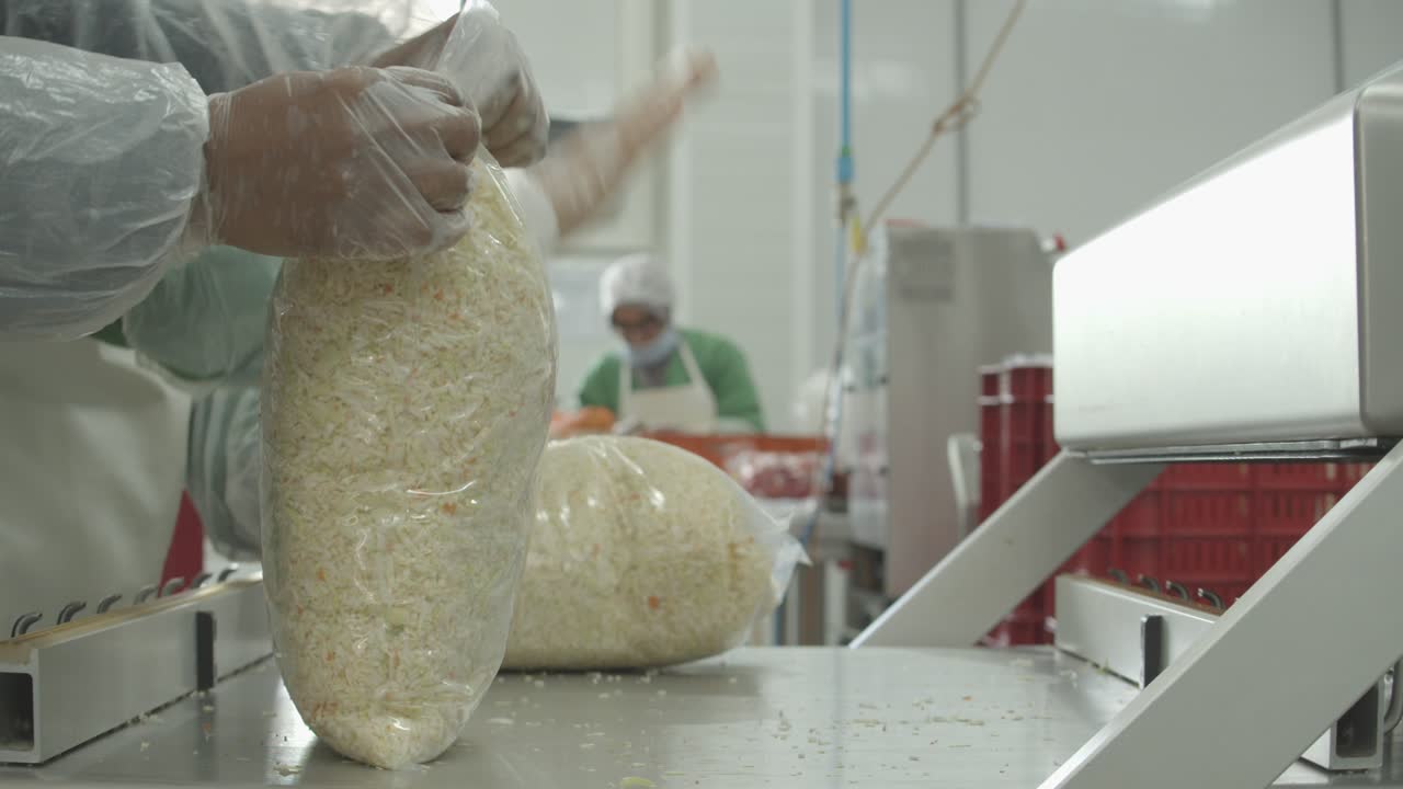 Workers packing raw uncooked rice in large plastic bags at the factory. Close up side view
