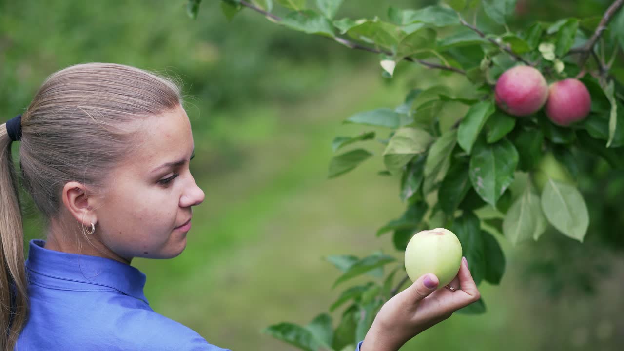 Beautiful girl in the garden holds a ripe apple in her hands