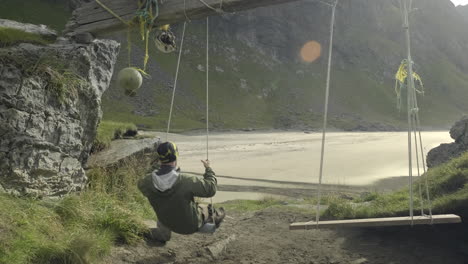 a man swinging in slow motion at kvalvika beach and enjoying the view in lofoten, norway