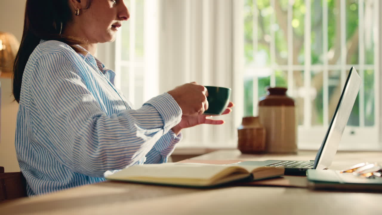 Woman Typing on Laptop and Drinking Coffee at Home