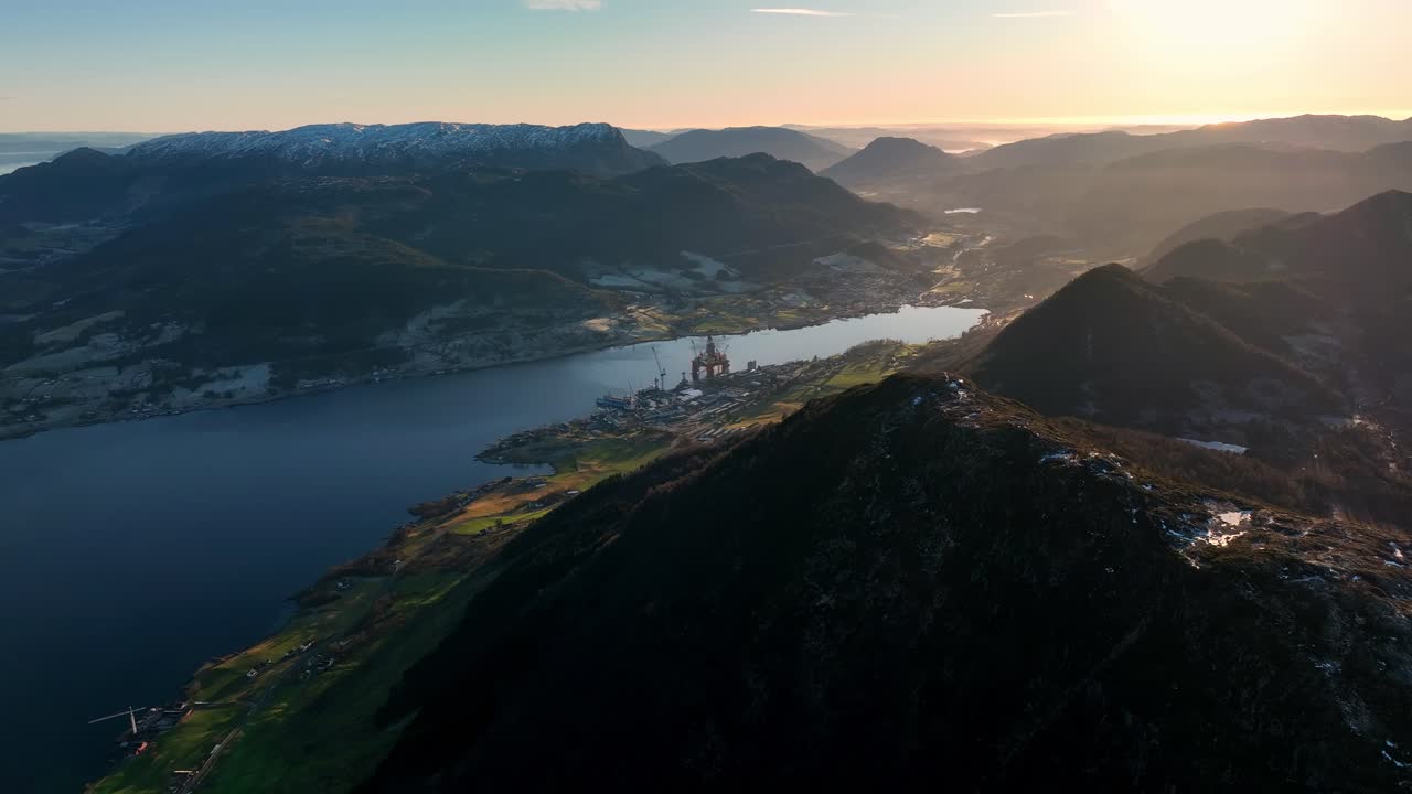 Aerial gliding left from mountain ridge in Vindafjord and Olen at sunset with fjord and mist below