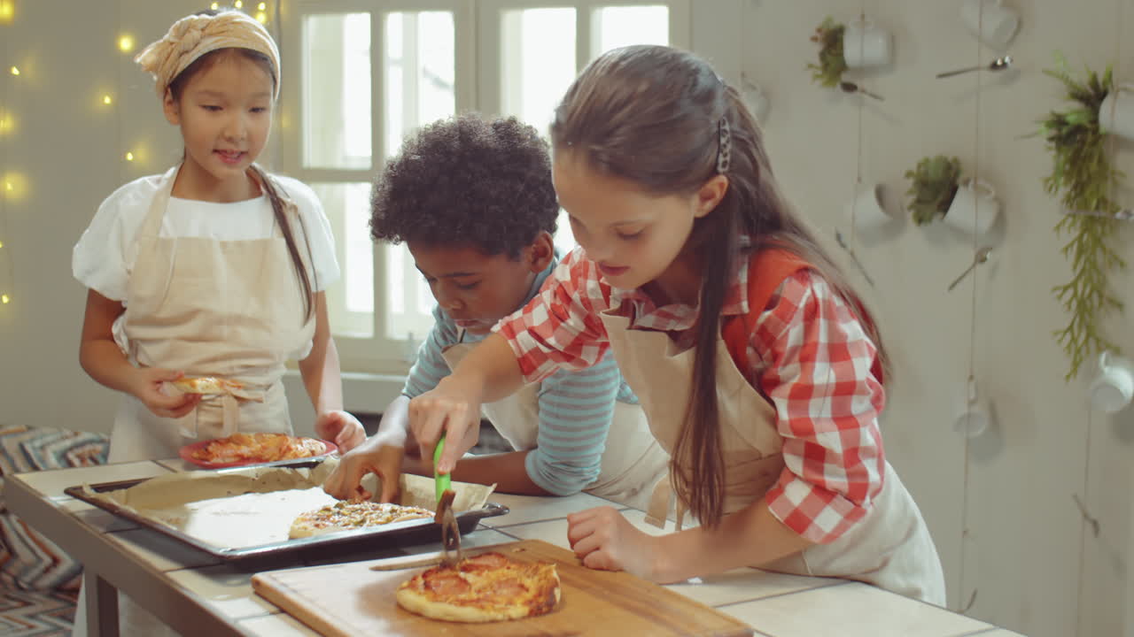 Bambini che tagliano e mangiano la pizza a una lezione di cucina