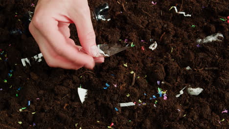hand cleaning up litter in soil