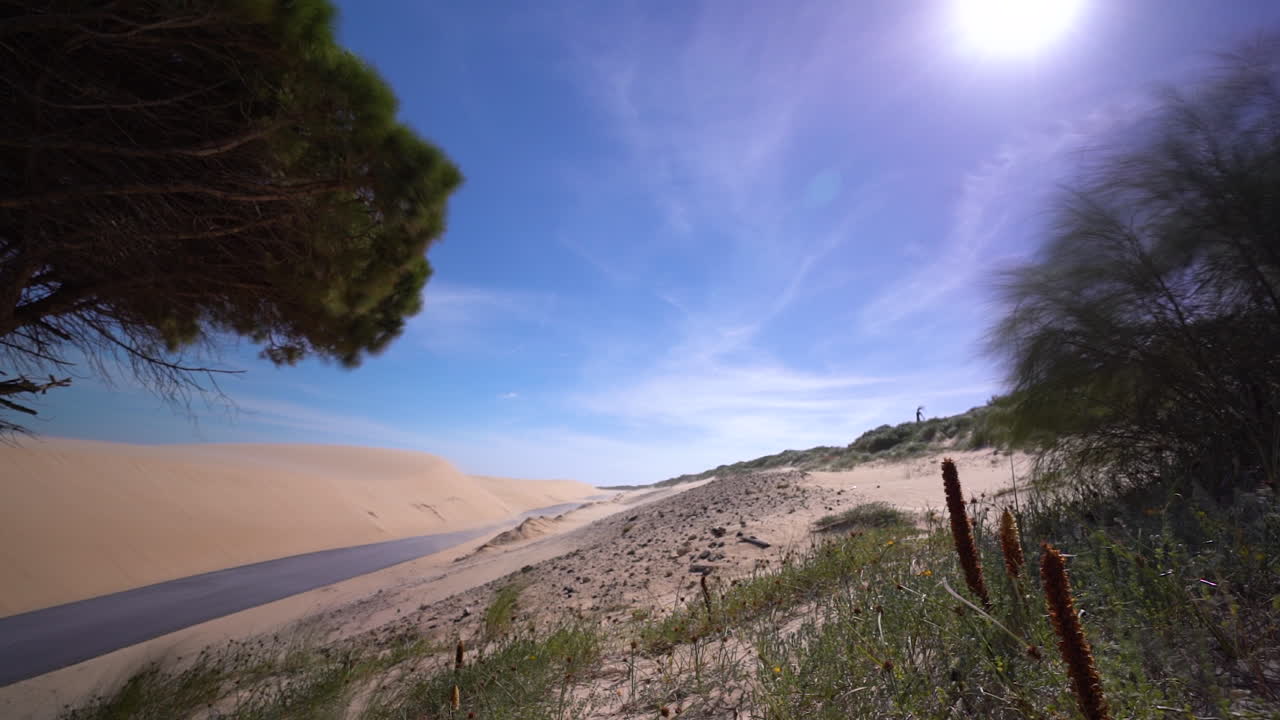 carretera de asfalto y dunas de arena en españa, lapso de tiempo en un día de viento