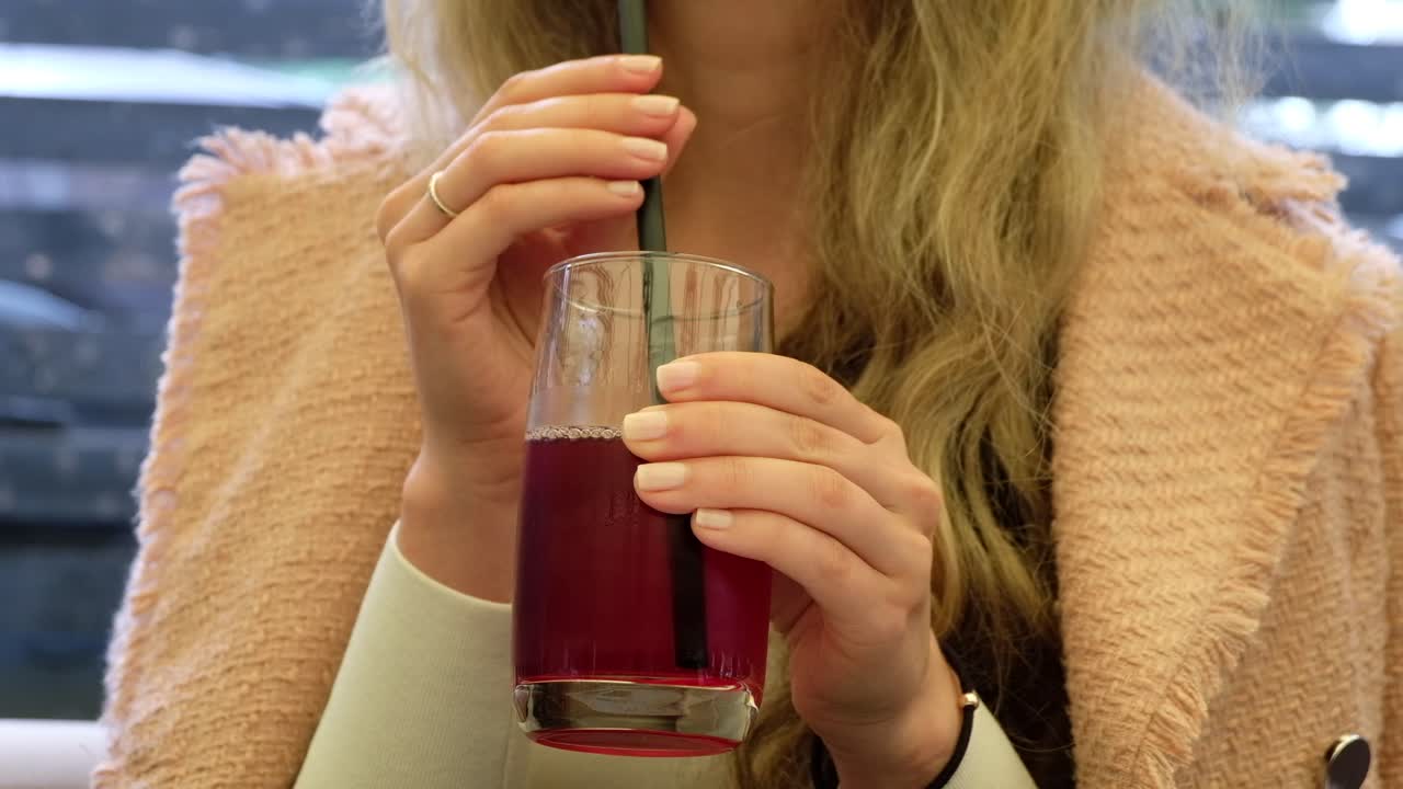 Close up of a woman drinking a red juice at a restaurant