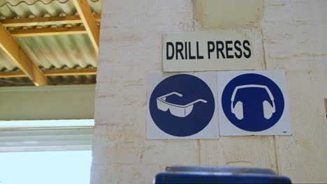 blue caution signs for ear and eye protection with drill press signage