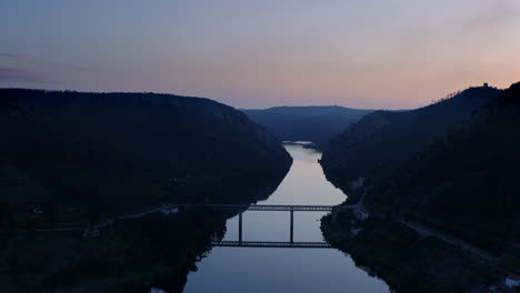 hermoso puente reflejo en el río, entre montañas de silueta