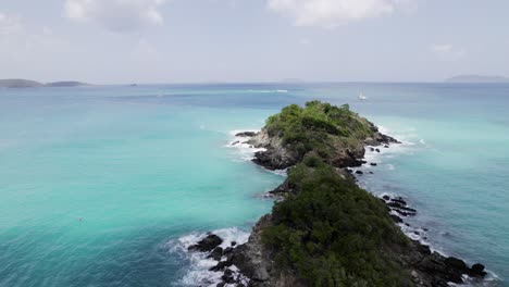 aerial drone wide shot passing by two archipelago islands water crashing on rocks boat yacht passing in the distance blue sky turquoise water white clouds