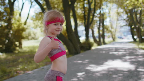 Back-view-of-athletic-sport-runner-girl-kid-training-marathon-run,-starting-race-showing-thumbs-up