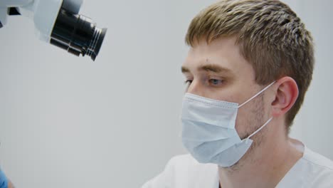 médico examinando al paciente con el microscopio