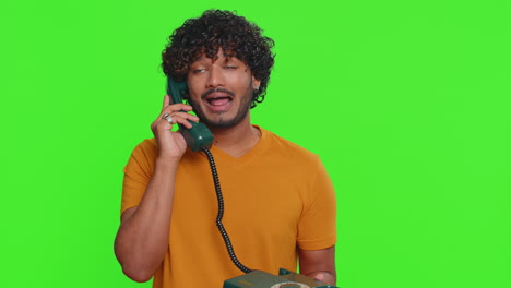 Crazy-funny-indian-man-talking-on-wired-vintage-telephone-of-80s,-fooling,-making-silly-faces