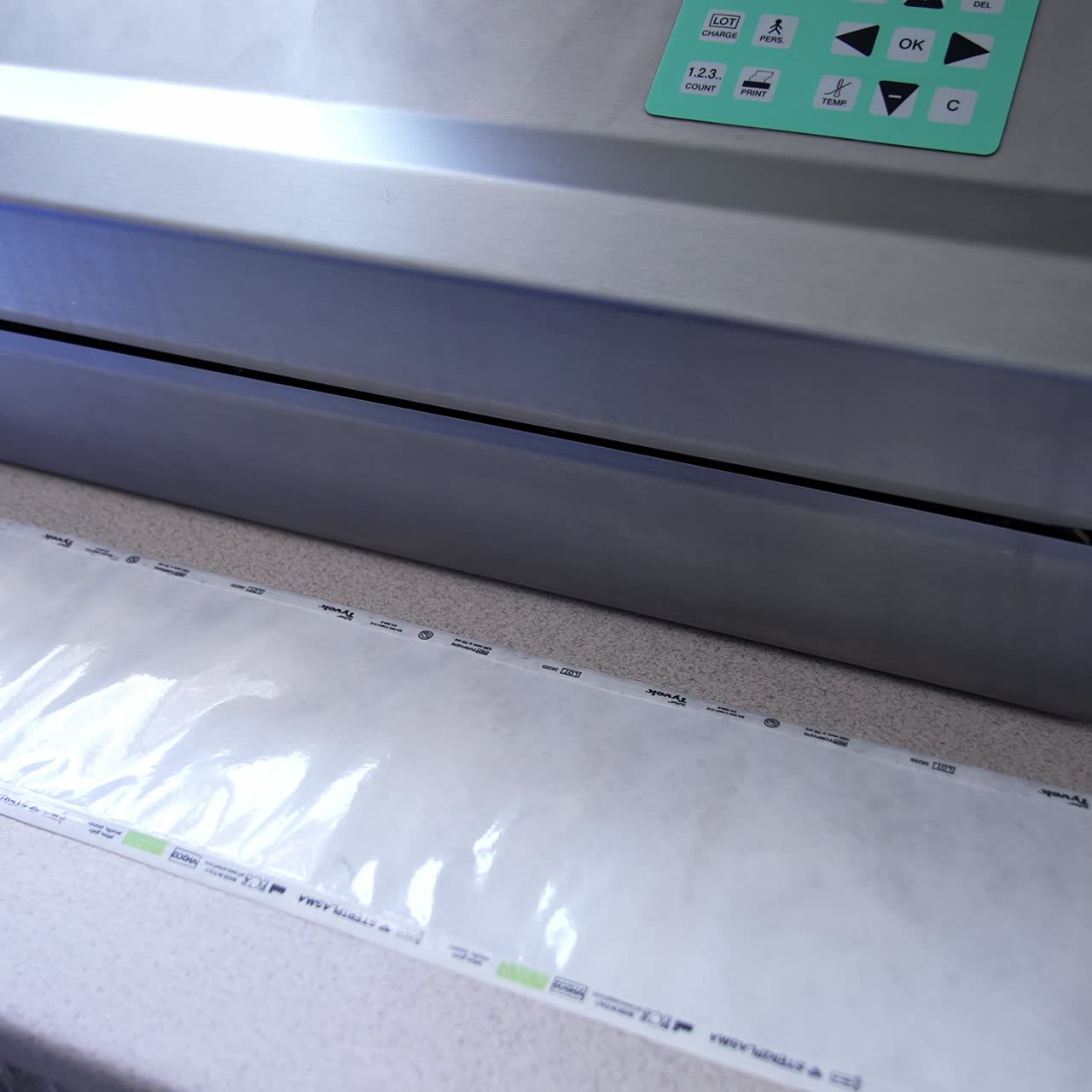 Panel of sensor keys on the equipment for sterilization. Nurse in blue gloves prepares plastic bag for device disinfection in machine. Top view