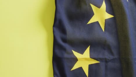 Video-Der-Zerknitterten-Flagge-Der-Europäischen-Union,-Die-Auf-Gelbem-Hintergrund-Liegt