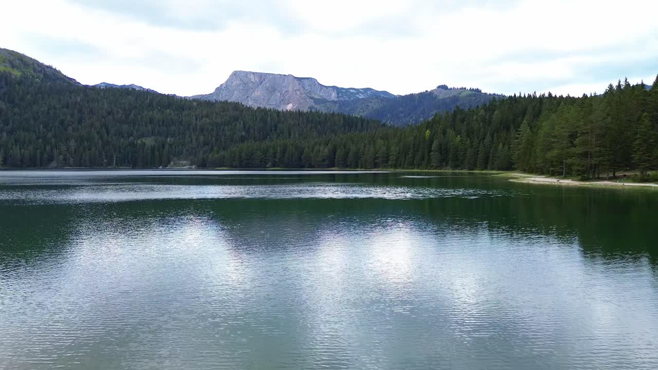 Vue aérienne du Lac Noir, un lac glaciaire du parc national de Durmitor entouré de forêts de conifères denses avec une montagne en arrière-plan, plan de situation