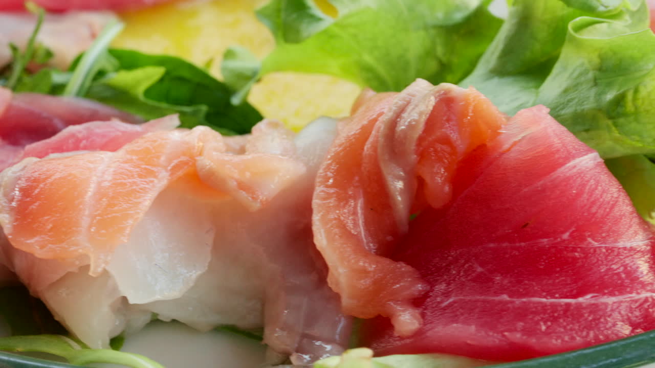 Primo piano di fette di pesce crudo fresco con verdure in un'insalata.