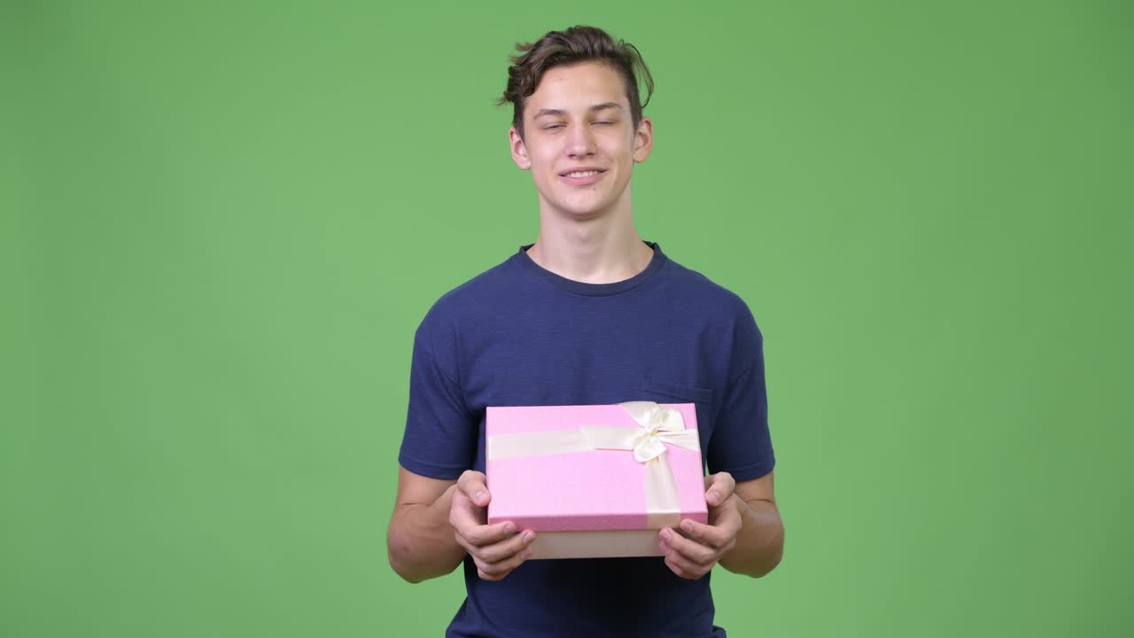 Young handsome teenage boy thinking with gift box