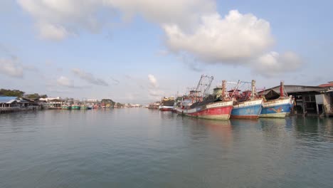 Aerial:-low-altitude-flight-towards-moored-fisherman-boats-and-ferries-in-thai-Harbour-in-Thailand