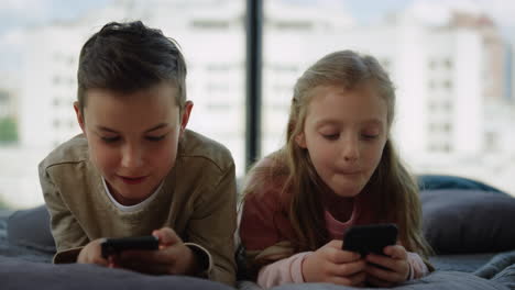 brother and sister gaming on mobile phones. siblings using smartphones at home.