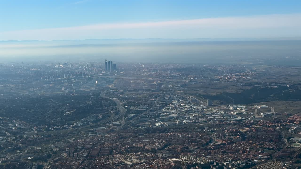 Vista aérea do centro da cidade de Madri e arredores cobertos por um céu poluído, capturada do cockpit de um avião em um dia de inverno.
