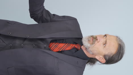 video vertical de un viejo hombre de negocios enojado mirando a la cámara.